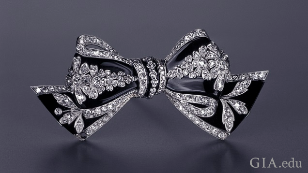 Bow brooch with stripe-like sections of black onyx between diamond sections.